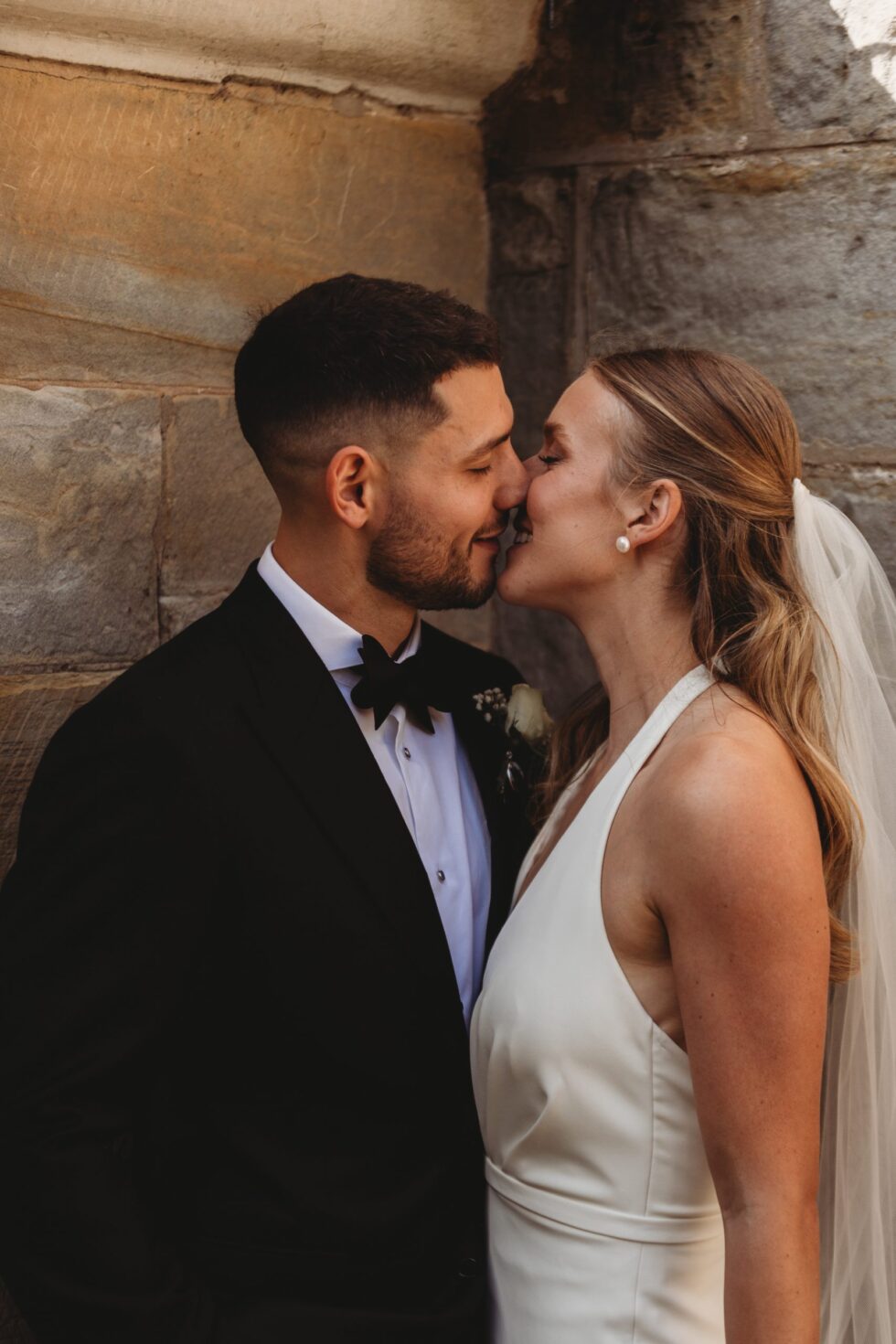 Bride and groom kissing outside of a church wedding in York, North Yorkshire. Groom is in a tux and bride is in a white dress